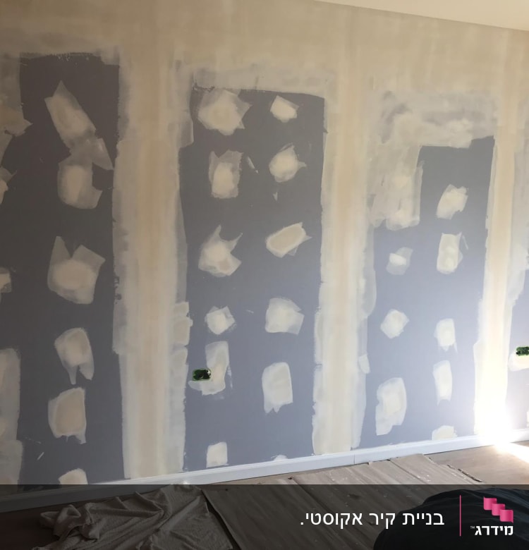 קיר עם תיקוני גבס וכתמי צבע לבנים